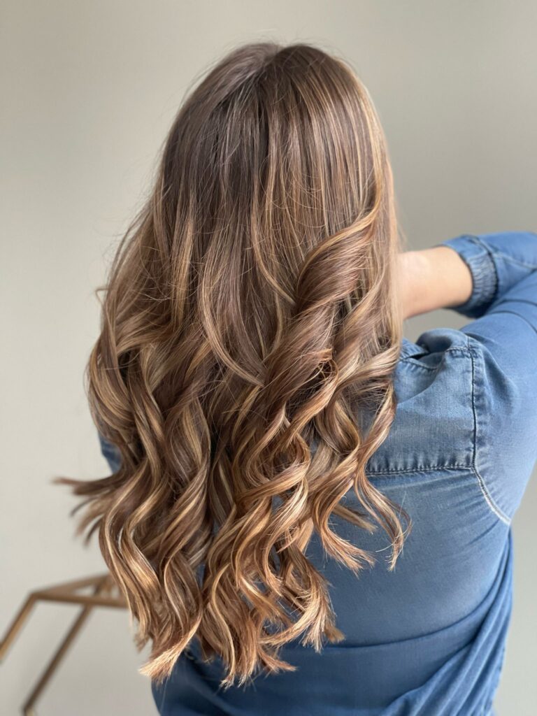 Curly brunette hair, denim jacket, back view.