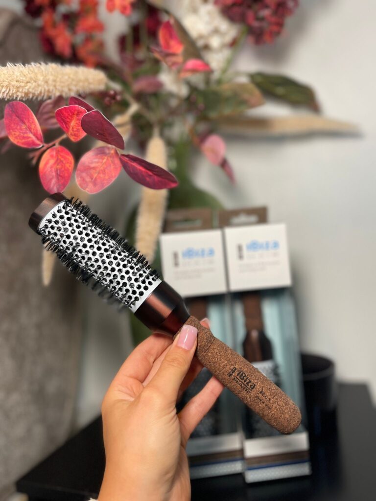 Round hairbrush held near decorative vase
